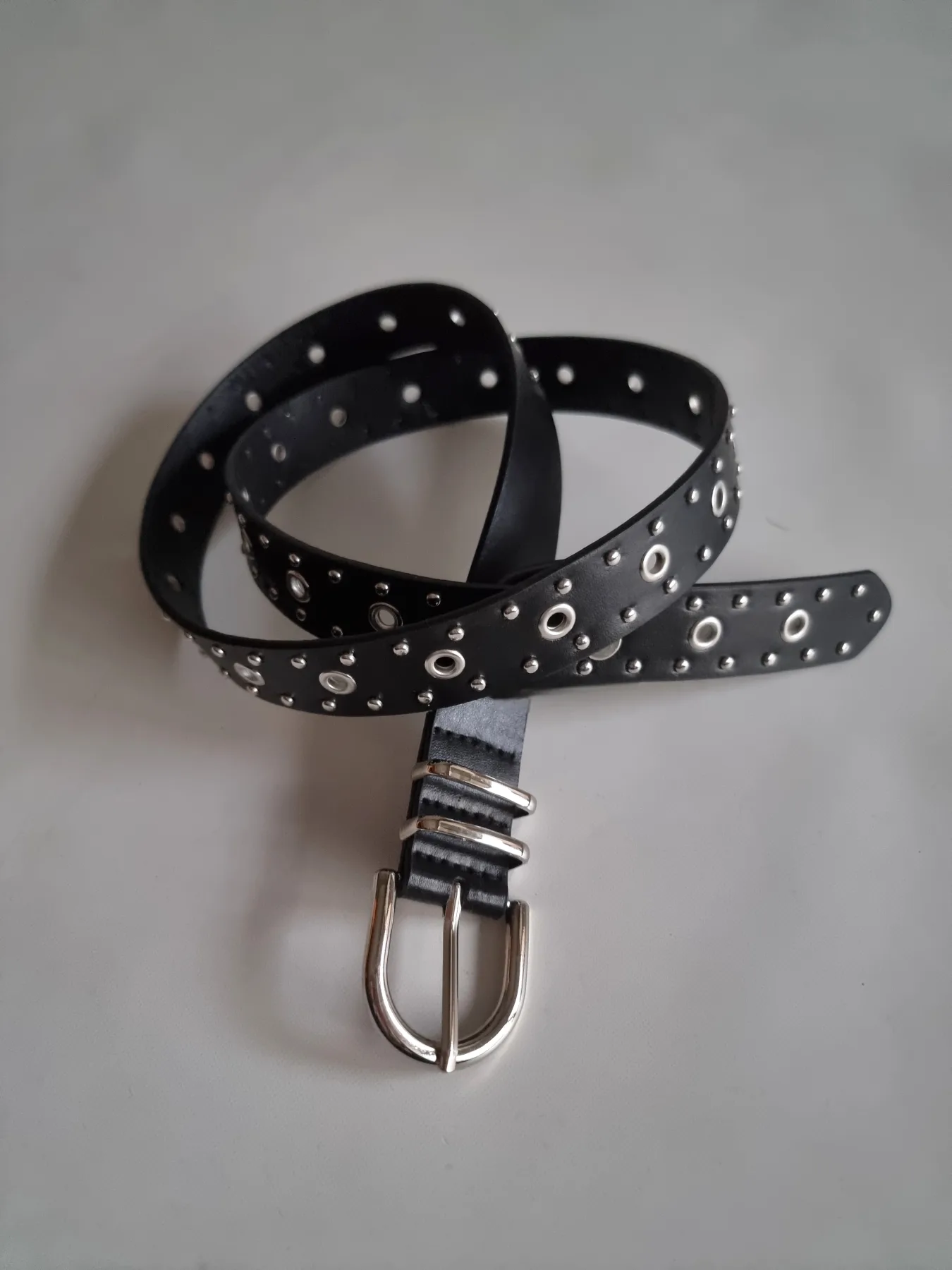 Cinturón negro con tachas y ojales metálicos